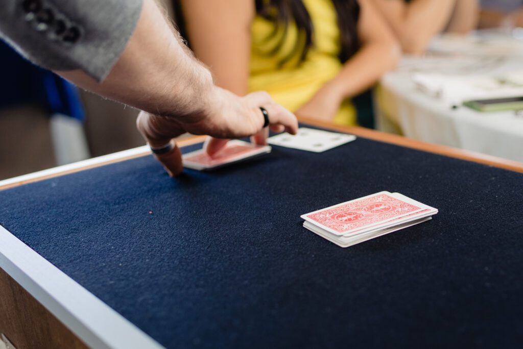A magician performs a trick with cards face down on a mat. A trade show magician performs a trick with cards face down on a mat. Close up magic.